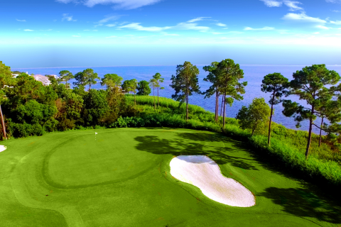 a view of a golf course with a view of the ocean.