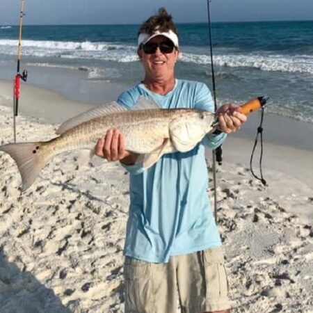 a man holding a fish on a beach.