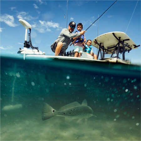 A family is fishing in a boat with a fish in the water.