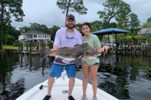 a man and a woman holding a fish on a boat.