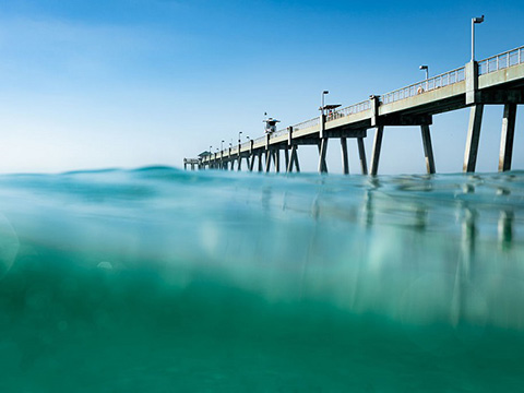a pier under the water with a blue sky.