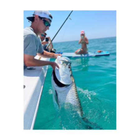 A man is holding a large fish in the water.