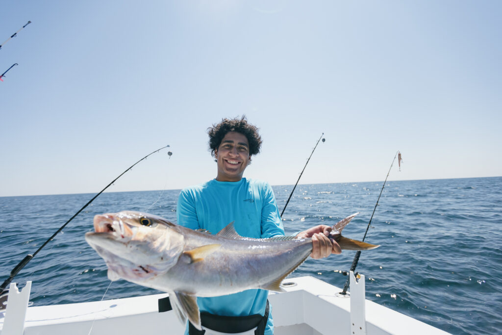 Man holding large fish on a boat in the ocean