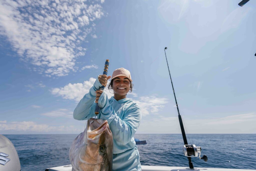 girl holding a fish on a boat in the ocean