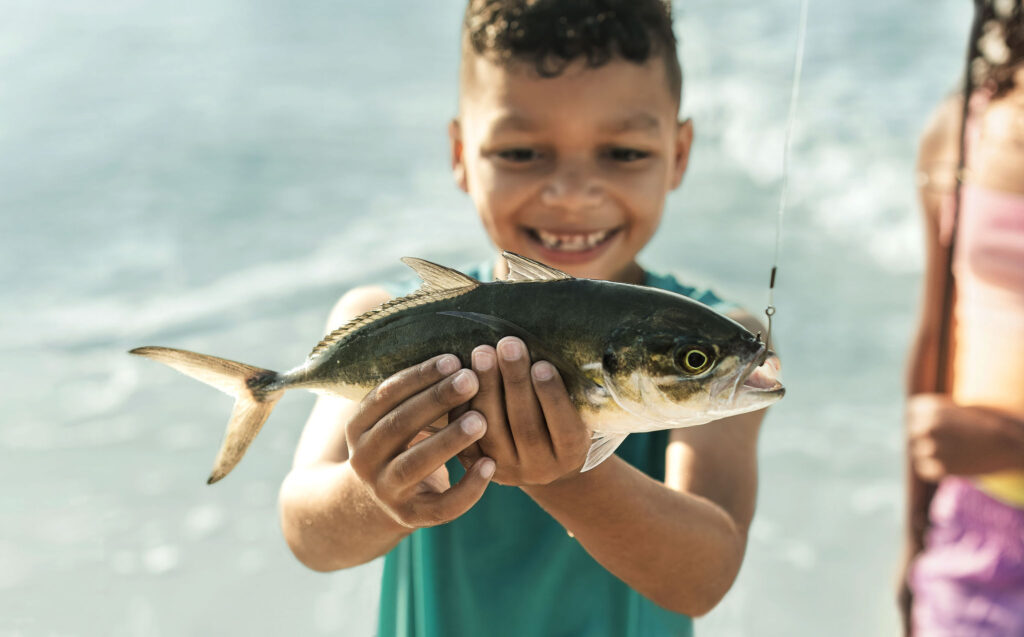 Young boy holding up a fish he caught