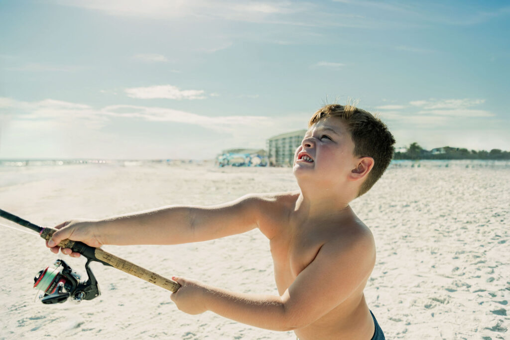 Boy holding a fishing pole on the beach