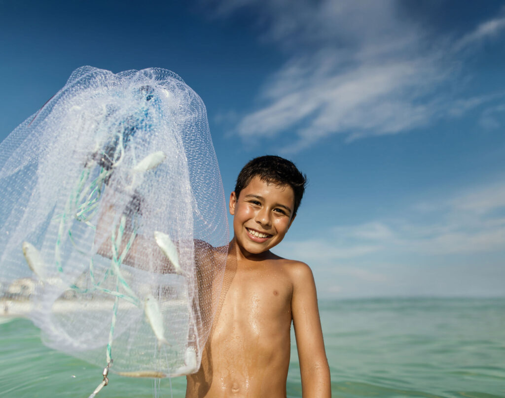 A young boy holds up a fishing net