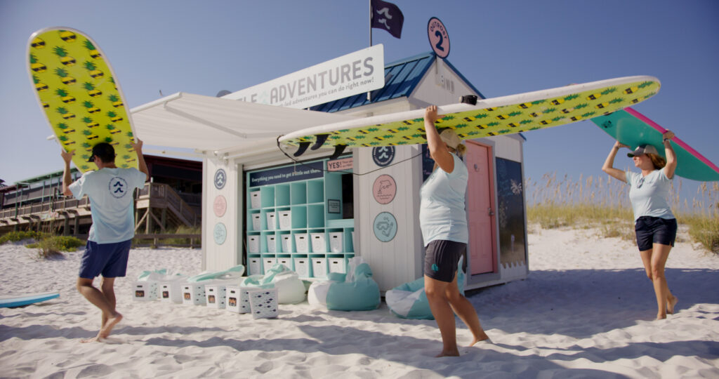 A woman holds a surfboard up above her head