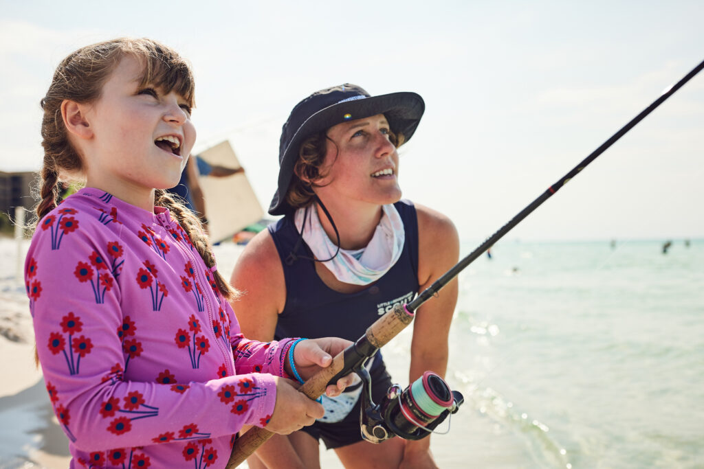An instructor with a young girl holding a fishing pole